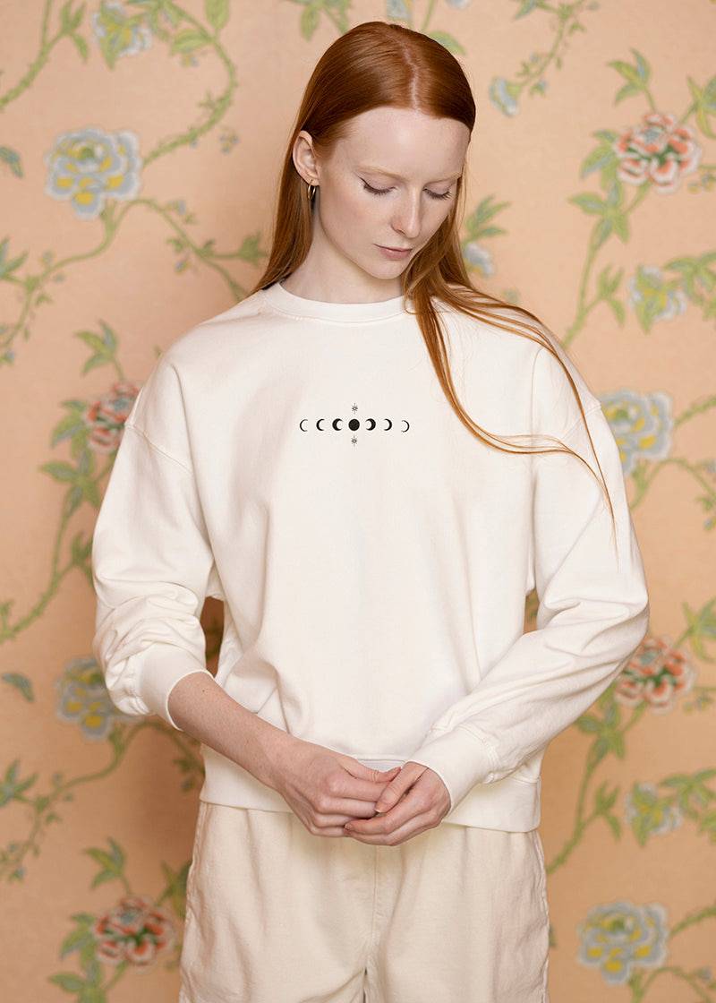 Gray crewneck sweatshirt featuring moon phases design from Sacred Light Soundbaths and Crystals, casual wear with celestial moon imagery.