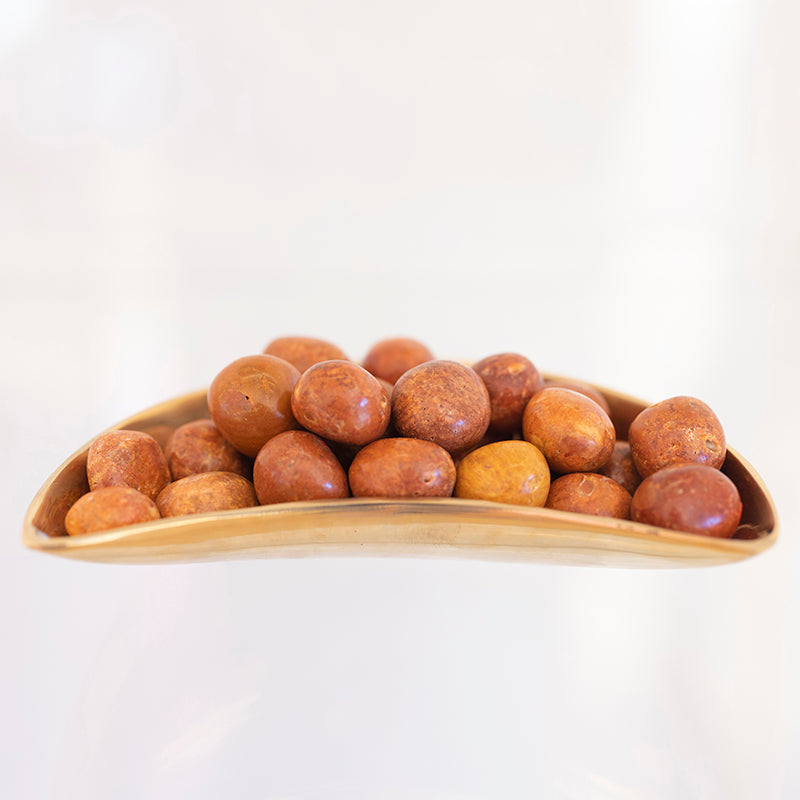 Smooth tumbled orange jasper stone from Sacred Light Soundbaths and Crystals, showcasing its warm, earthy orange hue.