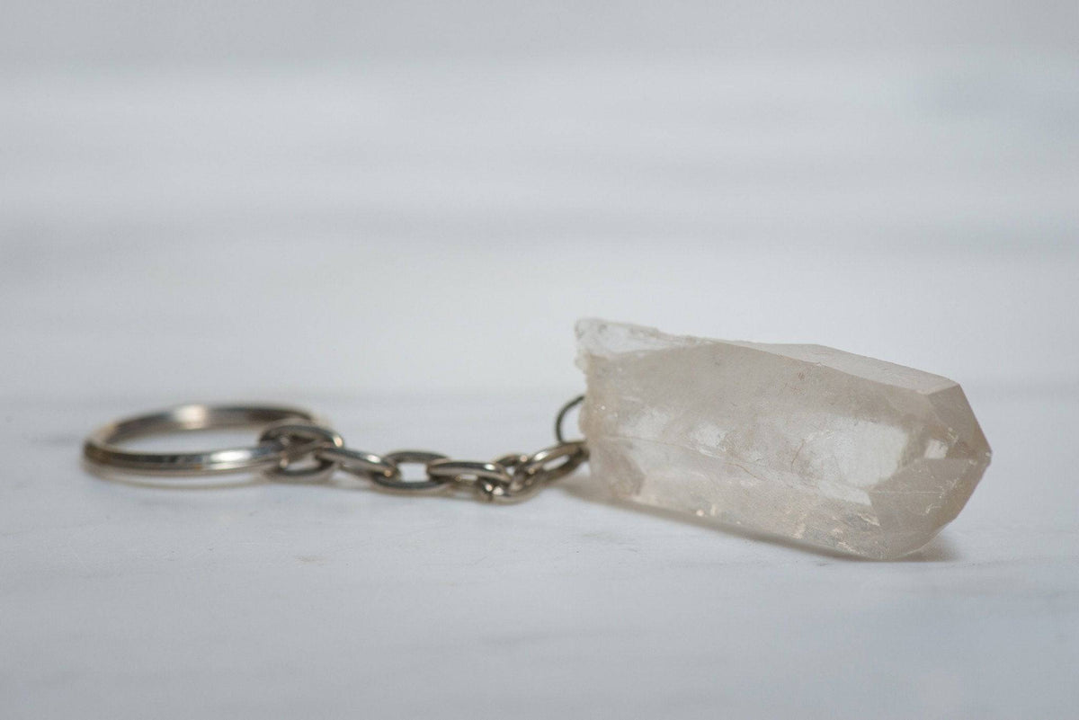 Clear quartz keychain from Sacred Light Soundbaths and Crystals featuring a polished, transparent crystal pendant on a metal keyring.