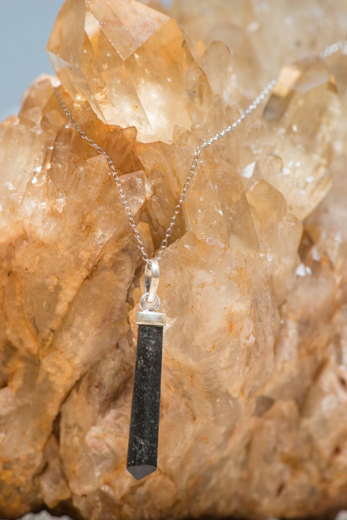 Polished black tourmaline pendant necklace from Sacred Light Soundbaths and Crystals, showcasing a sleek, glossy black stone on a silver chain.