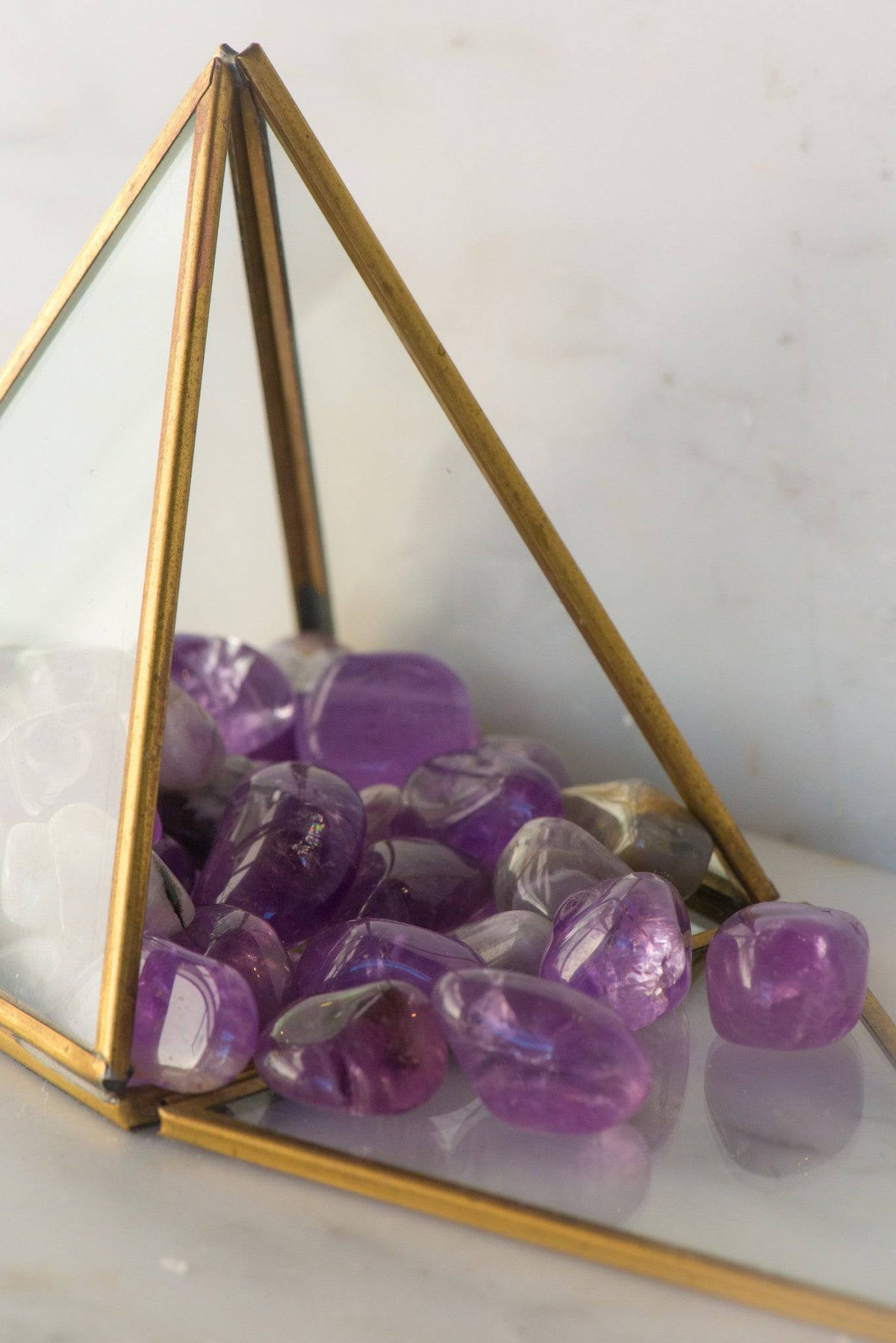 Tumbled amethyst stones from Sacred Light Soundbaths and Crystals displayed in a close-up view, showcasing their purple hues and smooth texture.