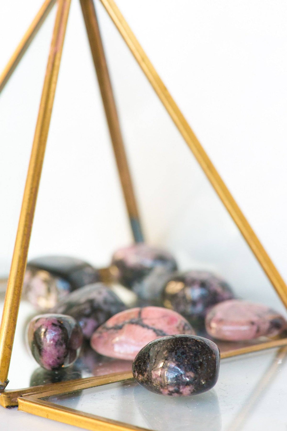Tumbled Rhodonite stone from Sacred Light Soundbaths and Crystals, showcasing smooth, pink and black patterned mineral stones.
