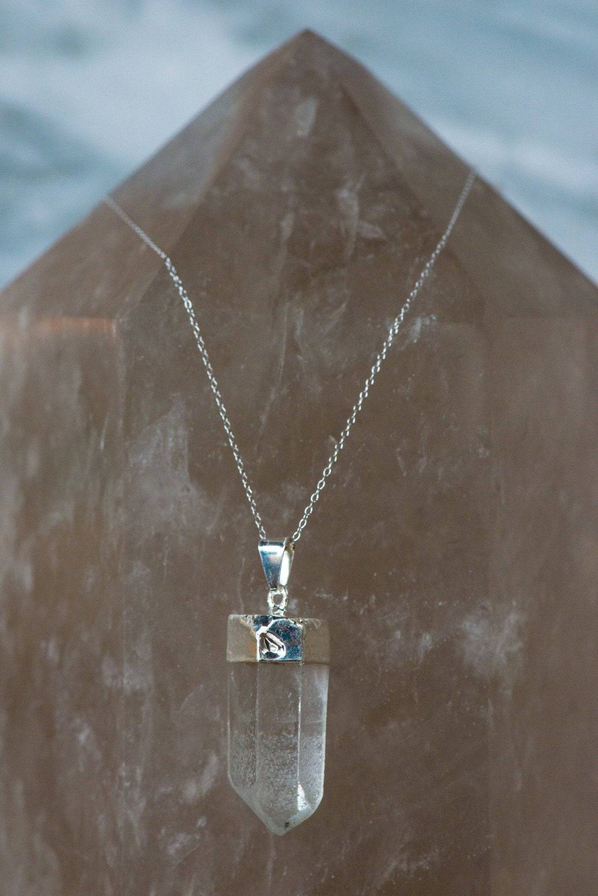 Clear Quartz Point necklace featuring a polished crystal pendant on a silver chain, jewelry by Sacred Light Soundbaths and Crystals.