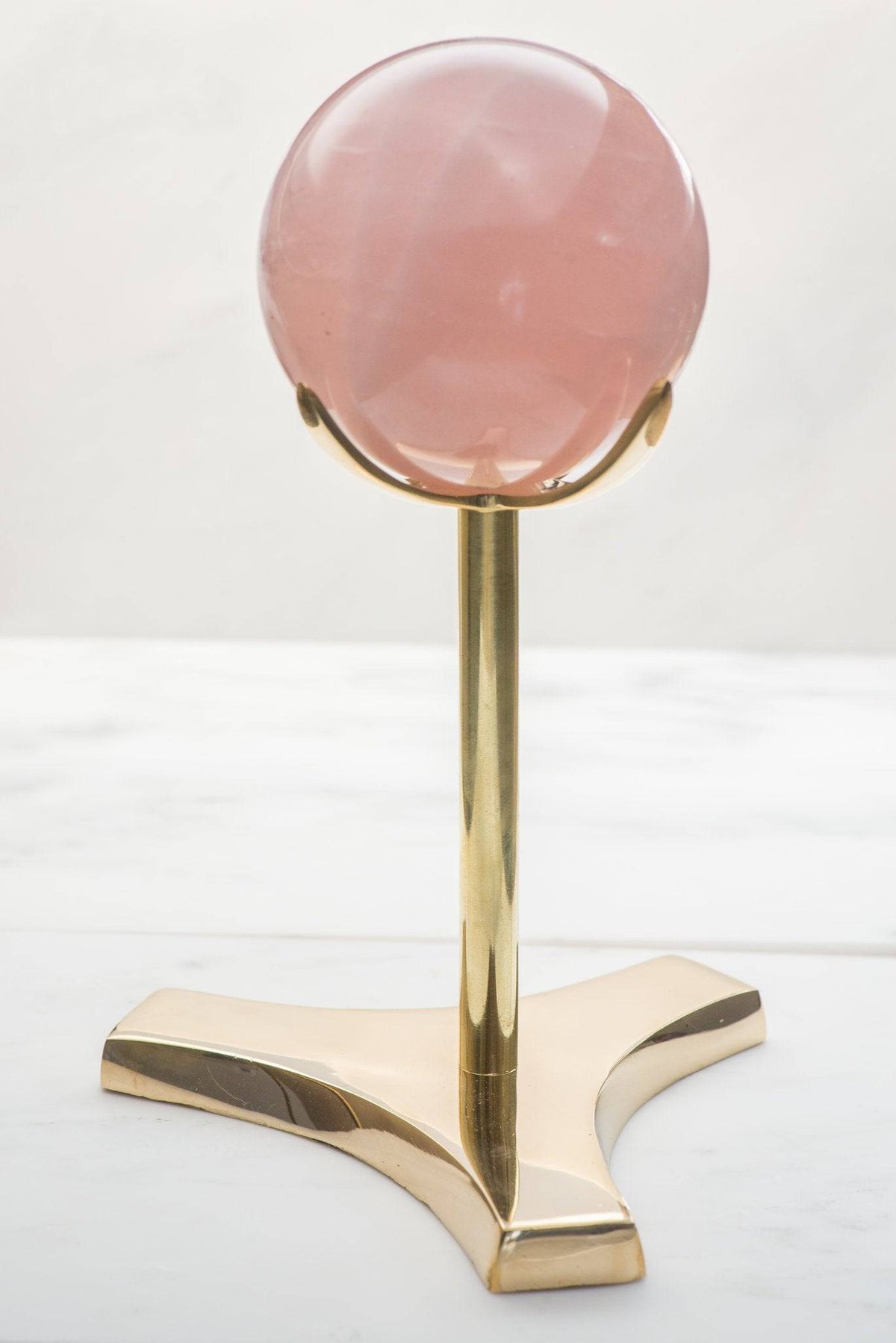 Brass 4-prong crystal specimen stand from Sacred Light Soundbaths and Crystals, showcasing a clear crystal on a decorative stand.