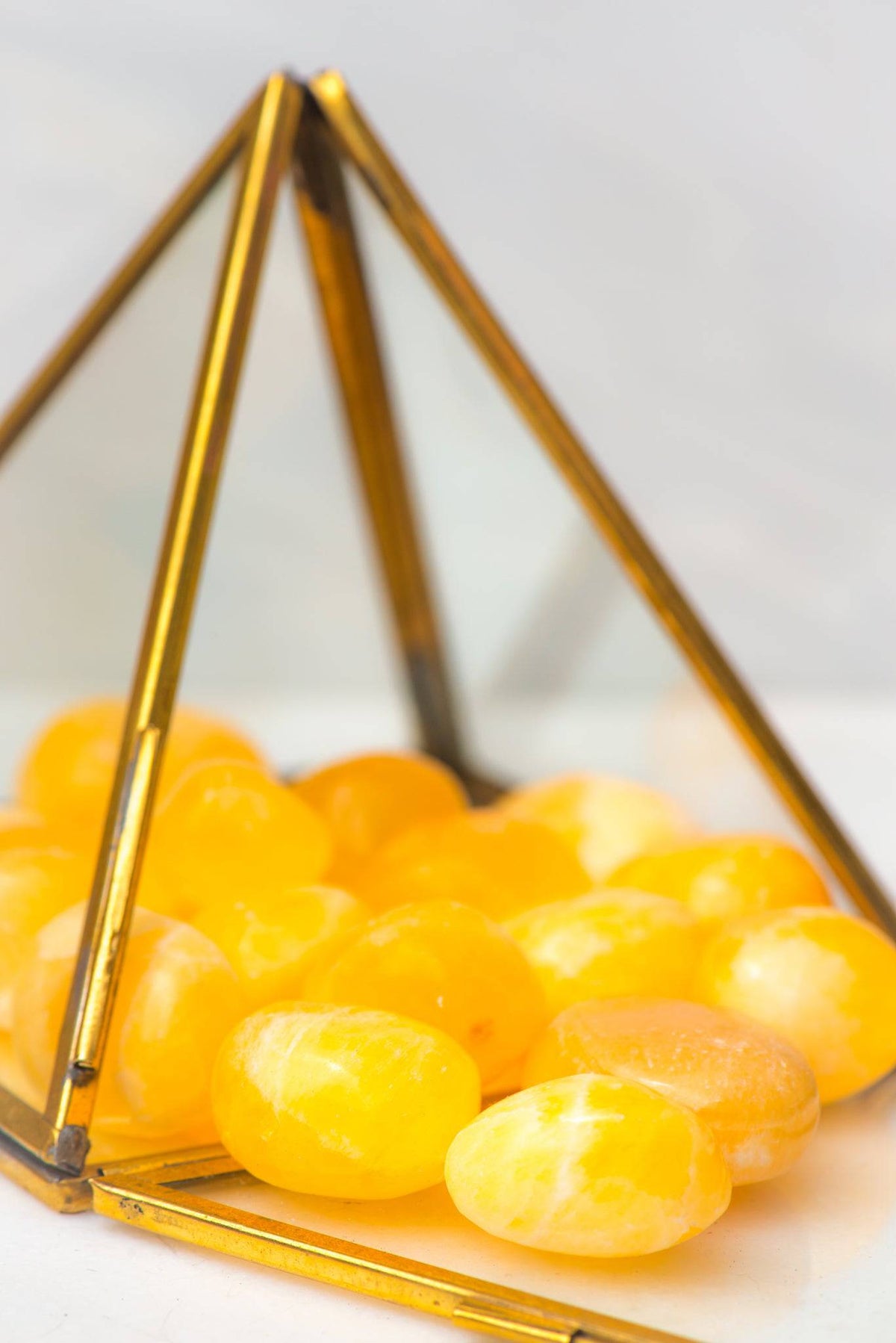 Smooth tumbled orange calcite stone from Sacred Light Soundbaths and Crystals, showcasing its vibrant orange color and polished surface.
