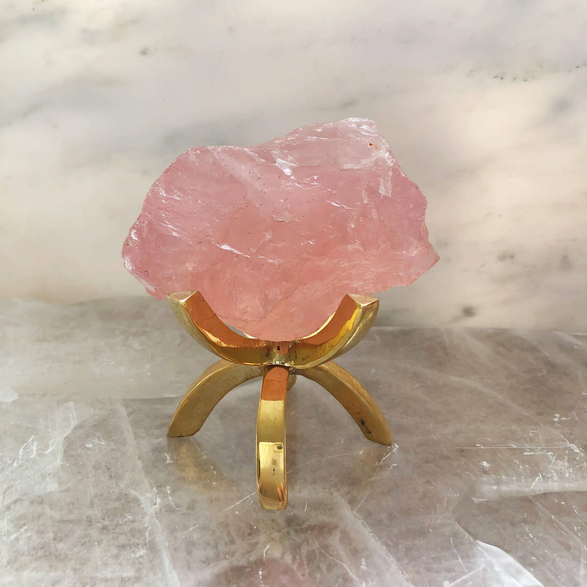 Rose quartz specimen displayed on a brass stand, showcasing its pink crystal clarity for Sacred Light Soundbaths and Crystals.