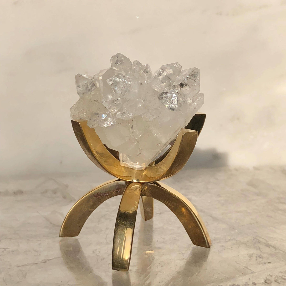 Beautiful apophyllite crystal with a brass stand, showcasing the translucent stone on a decorative display.