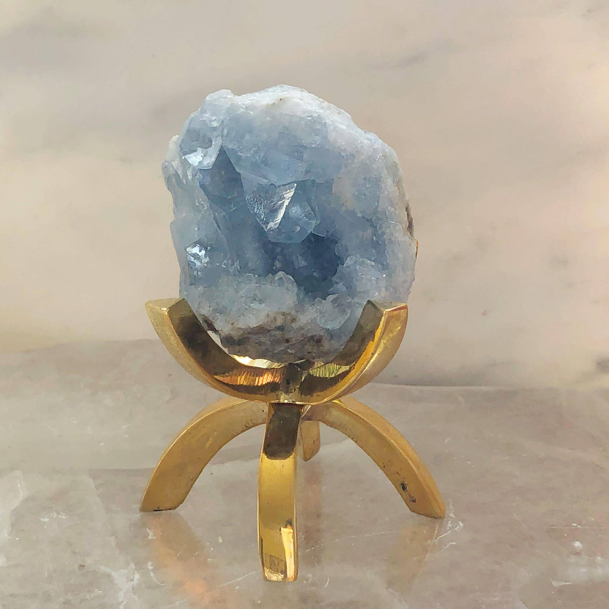 Celestite stone mounted on a brass stand, showcasing its blue crystalline structure, from Sacred Light Soundbaths and Crystals.