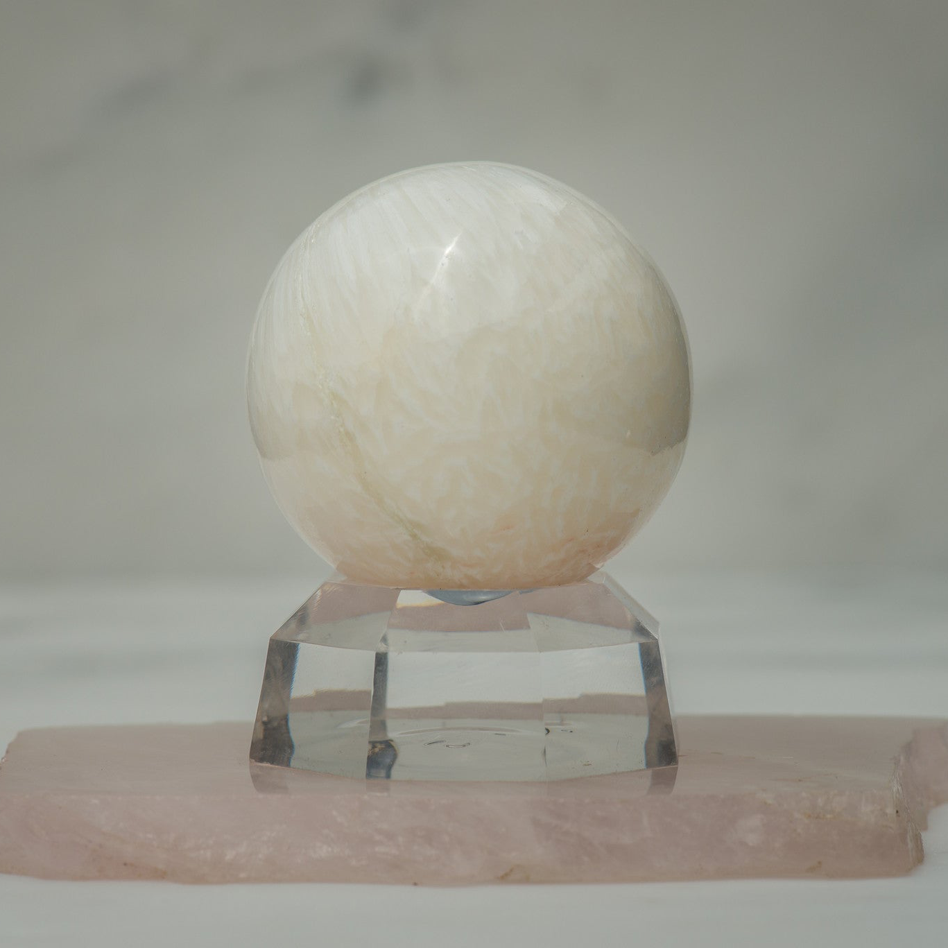 Polished Scolecite stone sphere from Sacred Light Soundbaths and Crystals, showcasing smooth, glossy surface and translucent white color.